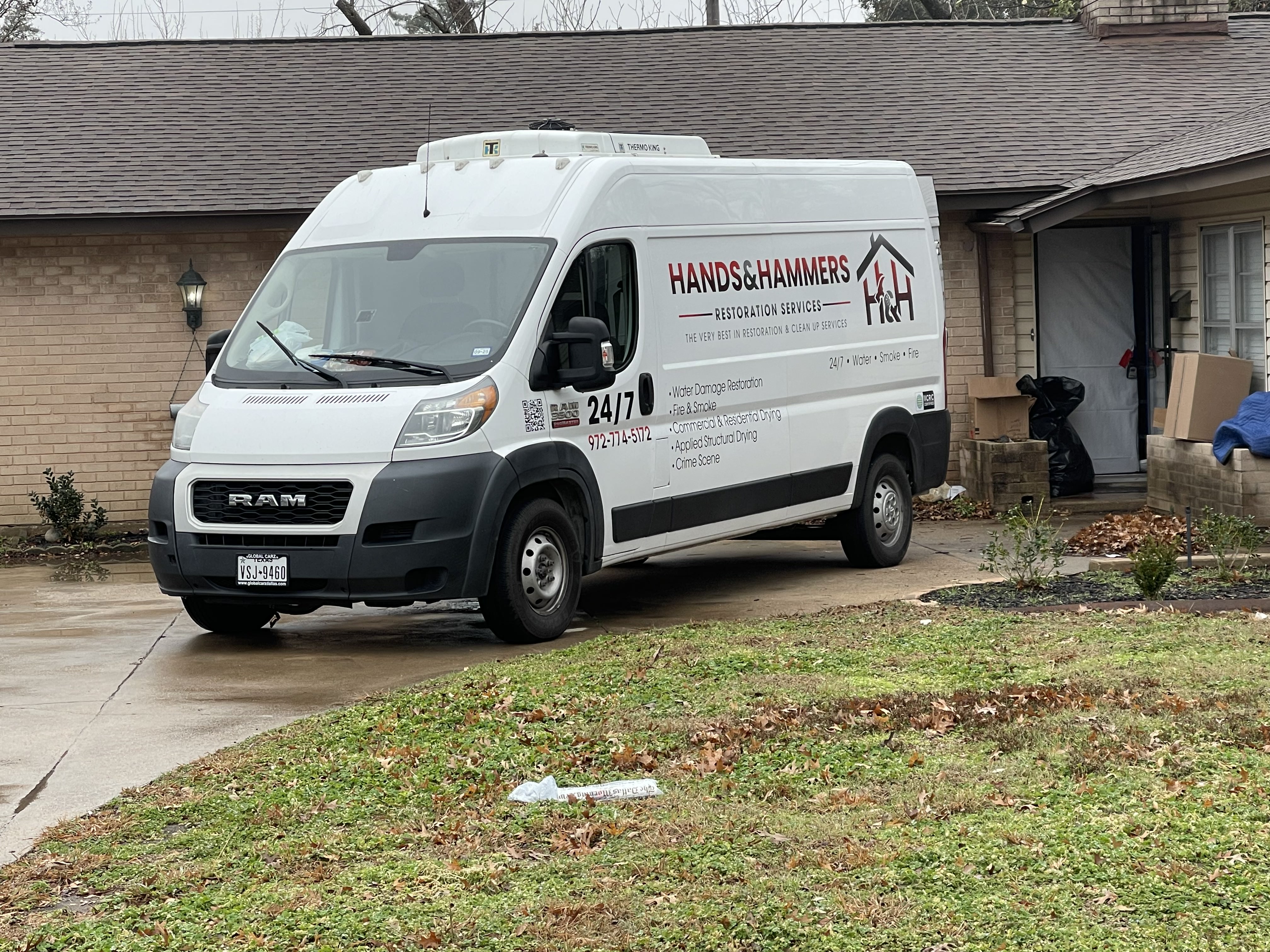An image of a white Hands & Hammers Restoration Services van parked outside a residential home.